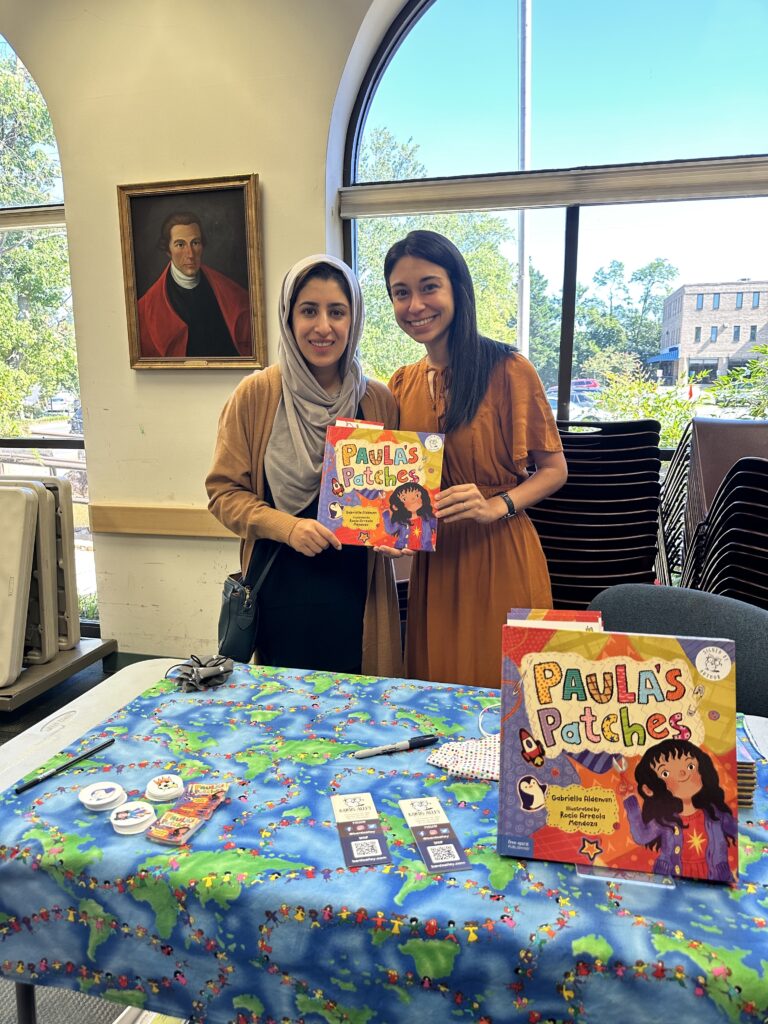 Humera and Gabriella hold up a copy of the picture book Paula's Patches